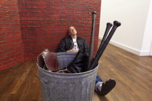 DENNIS TYFUS
Skins, Brains & Guts, 2020
polyurethane, hair, clothes, metal garbage
bin, wooden wall covered with plastic bricks,
acrylic and bistre, sandals, Dr. Martens boots,
wooden baseball bats, 1 cigarette
250 x 320 x 240 cm photo: We Document Art 
